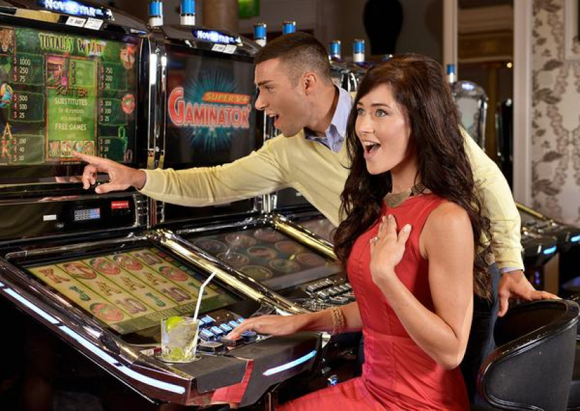 Couple excitedly playing on slot machines.