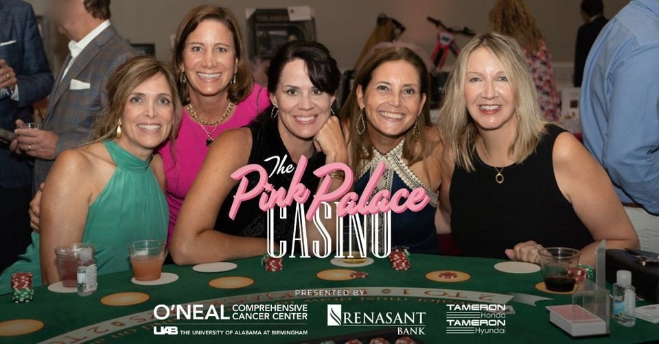Five women smiling at casino event table.