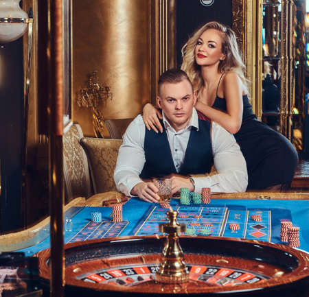 Couple at roulette table in luxurious casino.