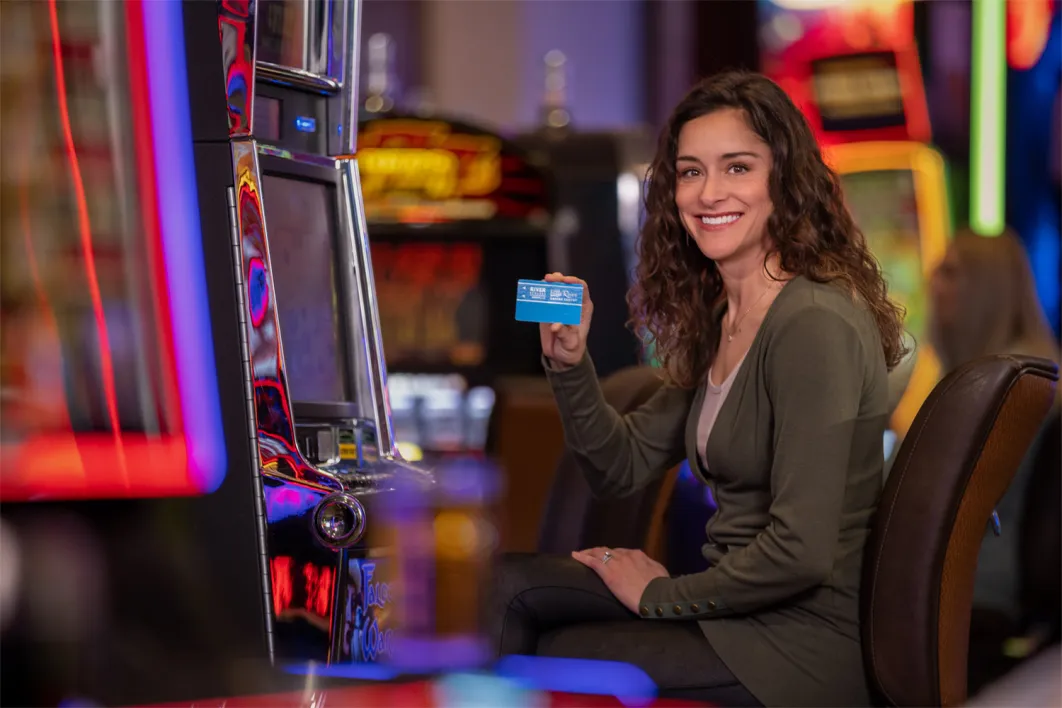 Woman smiling at slot machine with card.