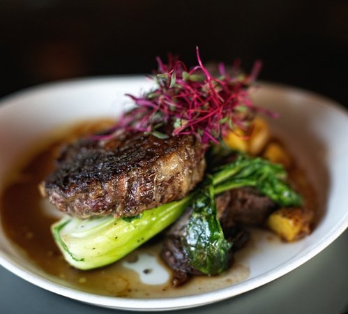 Steak with greens and garnish on plate.