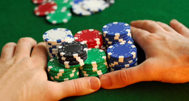 Hands holding colorful poker chips on table.
